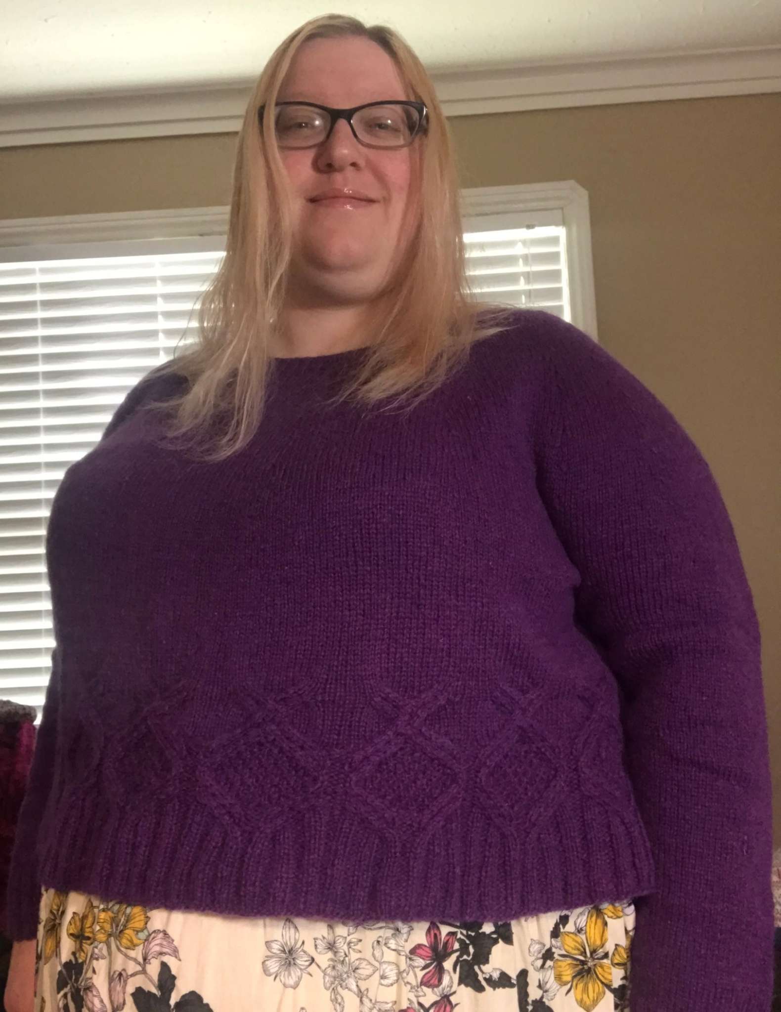 a model with blond hair and glasses wearing a purple sweater with cabled hem