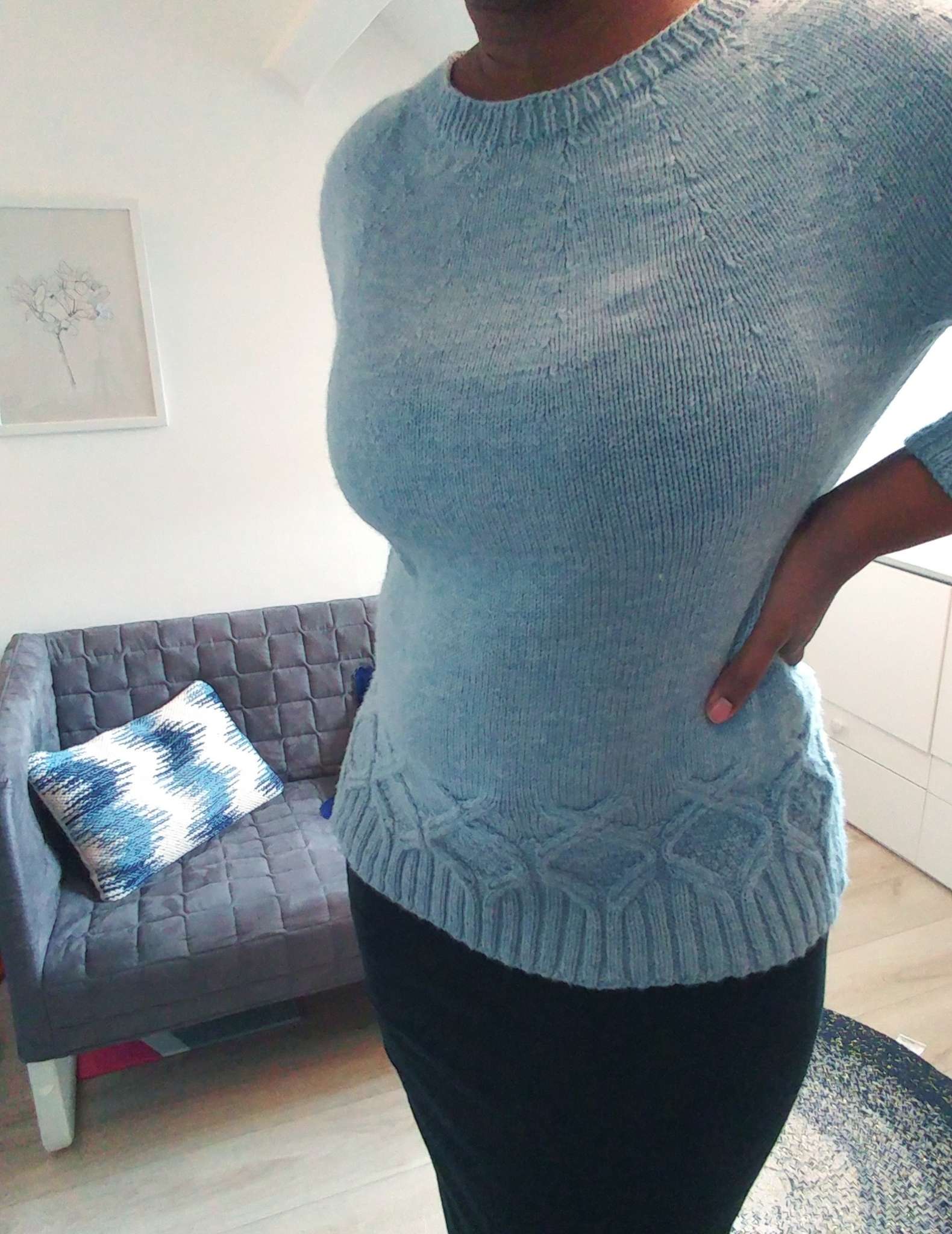 a close up of a modelled pale blue sweater, with a hand on one hip