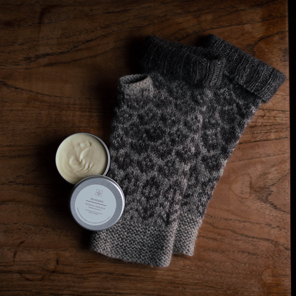 flat lay photo of brown mitts on a wooden table with an open tin of hand cream