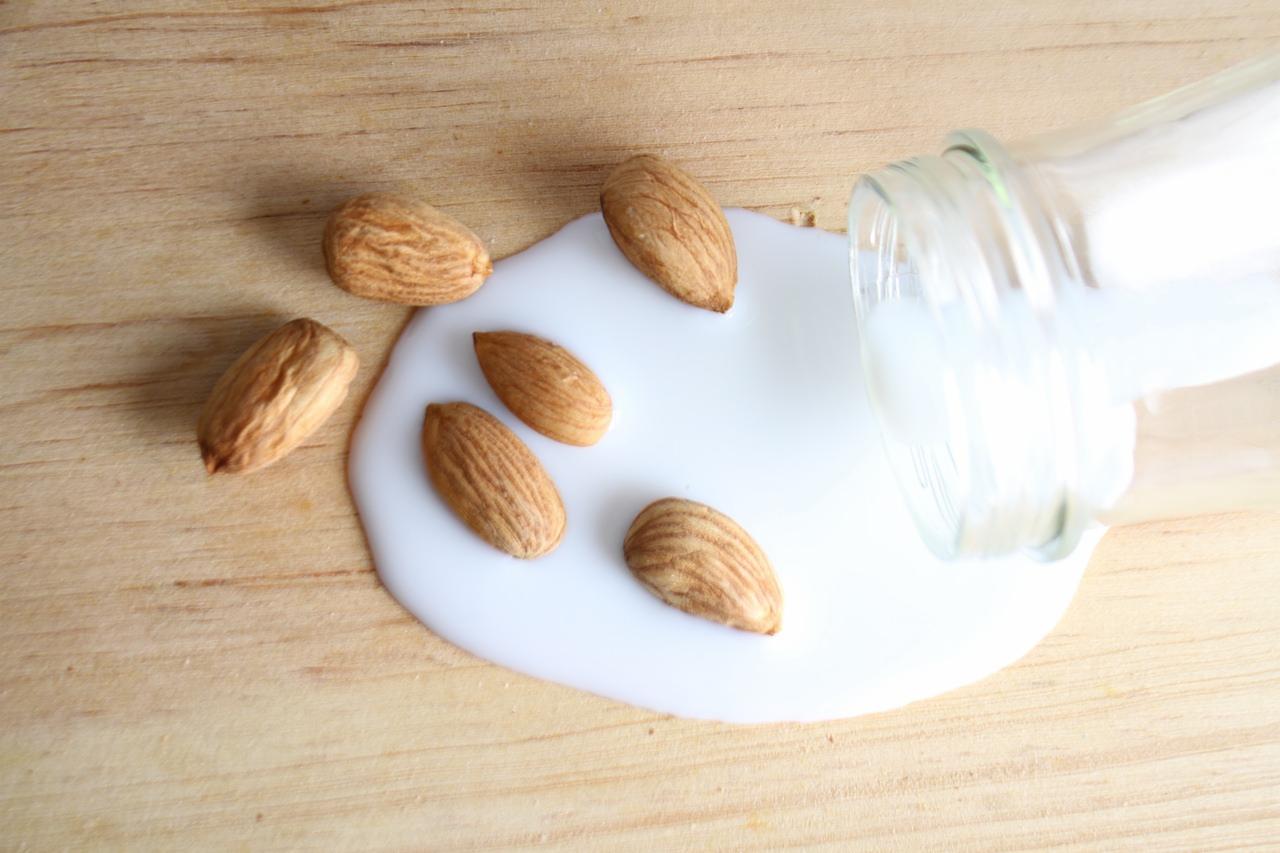 A scattering of almonds amongst a puddle of almond milk