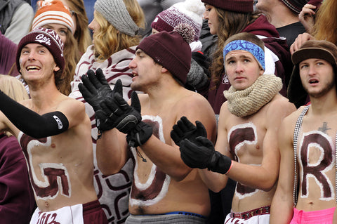 Shirtless students with G R I Z on their chests in maroon cheer during a Grizzly football game.