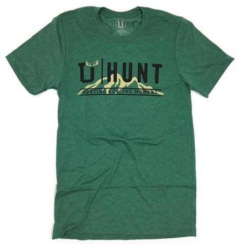 Green shirt with the beige outline of a mountain that says U Hunt Hunting for the moment.