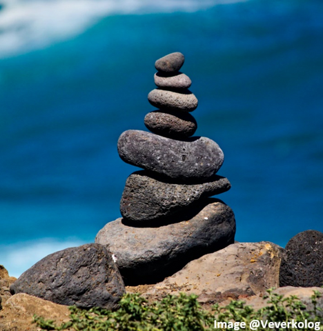 a spa looking stack of river rocks that are charcoal gray with a blue ocean backdrop