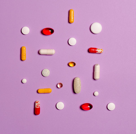 an assortment of different colors and shapes of pills against a purple background