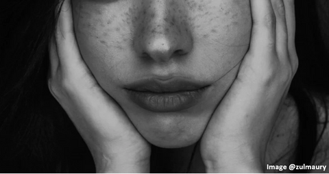 teenage brunette girl with cropped picture of her lips and her holding both sides of her face