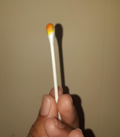 white q tip with an orange liquid on the tip