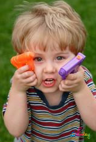 Toddler holding squirt guns up close to his face