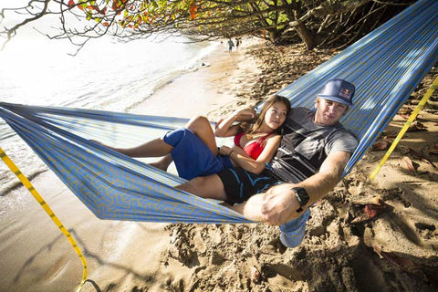 a couple sitting in a hammock on the beach