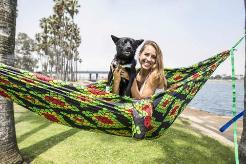 woman with her dog in a green and red patterned hammock