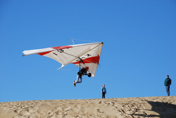 person hang gliding above a sand dune