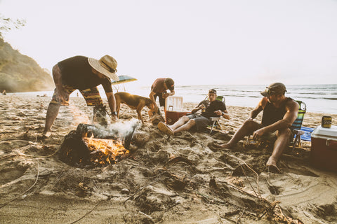 Group of friends hanging out by a camp fire on the beach