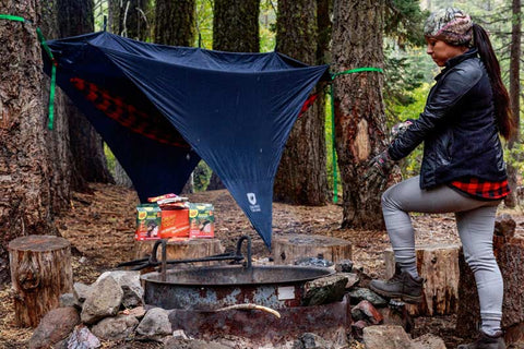 Woman setting up her hammock at a campsite