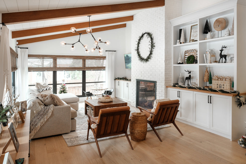 Living room with wooden ceiling beams exposed brick fireplace painted white and natural white oak hardwood floors