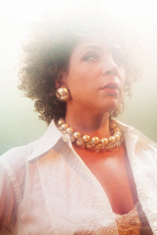 Sylvia Holden wears 70s pearl and lucite necklace and earrings in a wash of white light