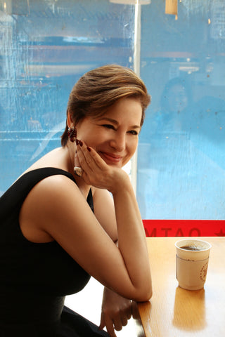 Celia Berk in a black dress and Icon Style jewelry in a coffee shop