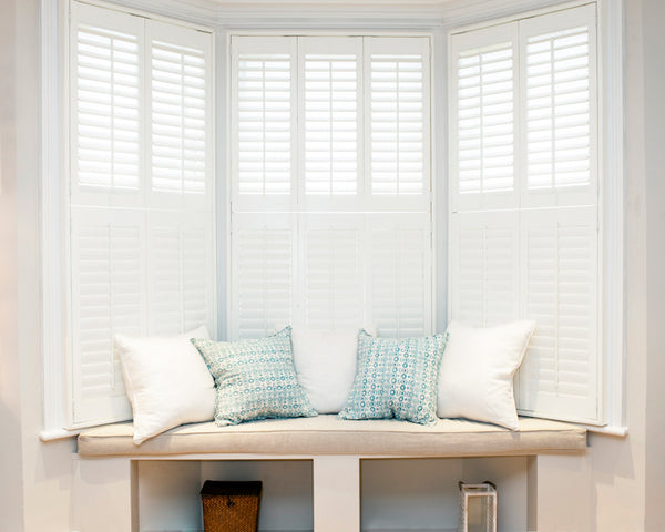 image of a bay window with a sofa and dressed with white shutters