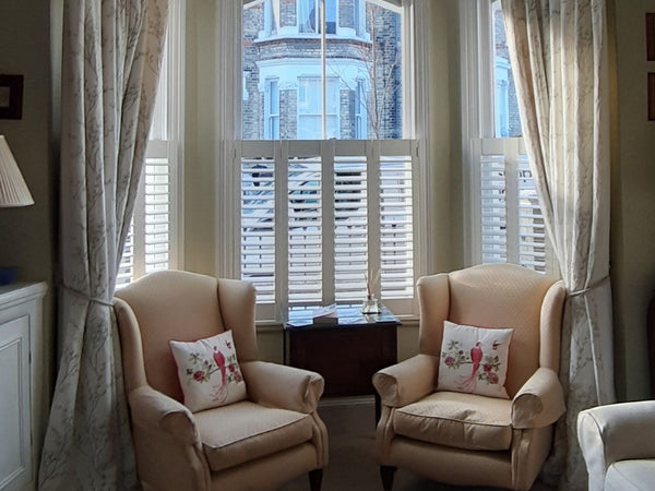 window with shutters and curtains with two armchairs in front