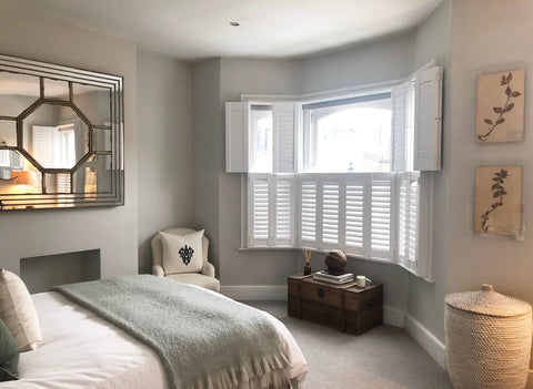 large bedroom with bay window and tier on tier shutters half open