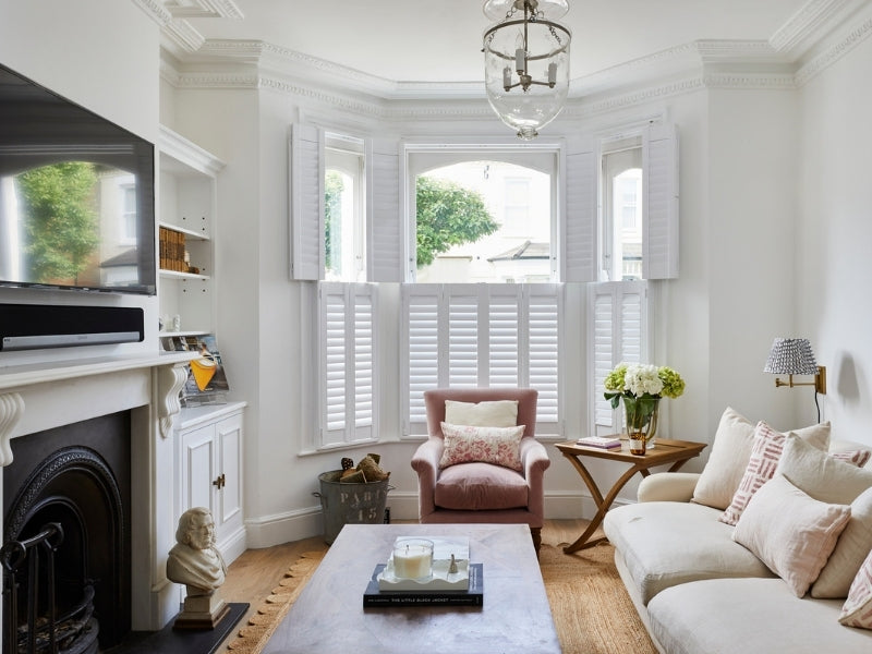 tier on tier shutters in a lounge with chimney and white sofe