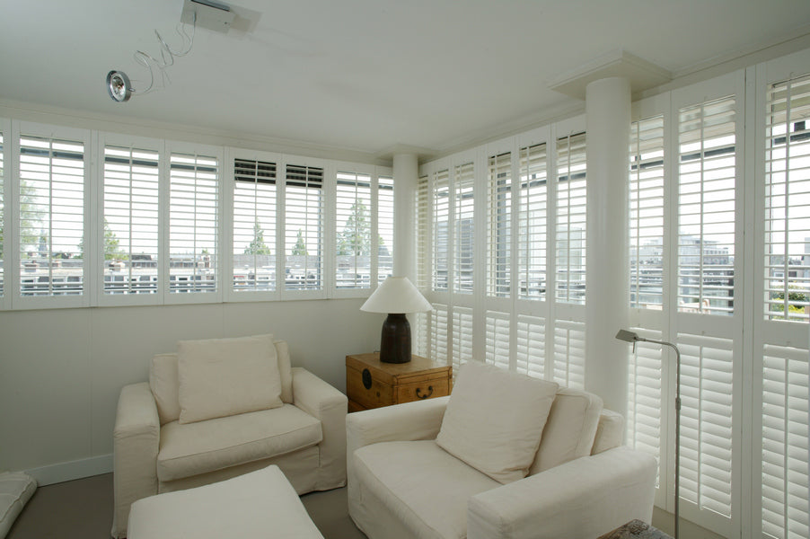 fully illuminated modern living room dominated by white colours, with white shutters on the windows