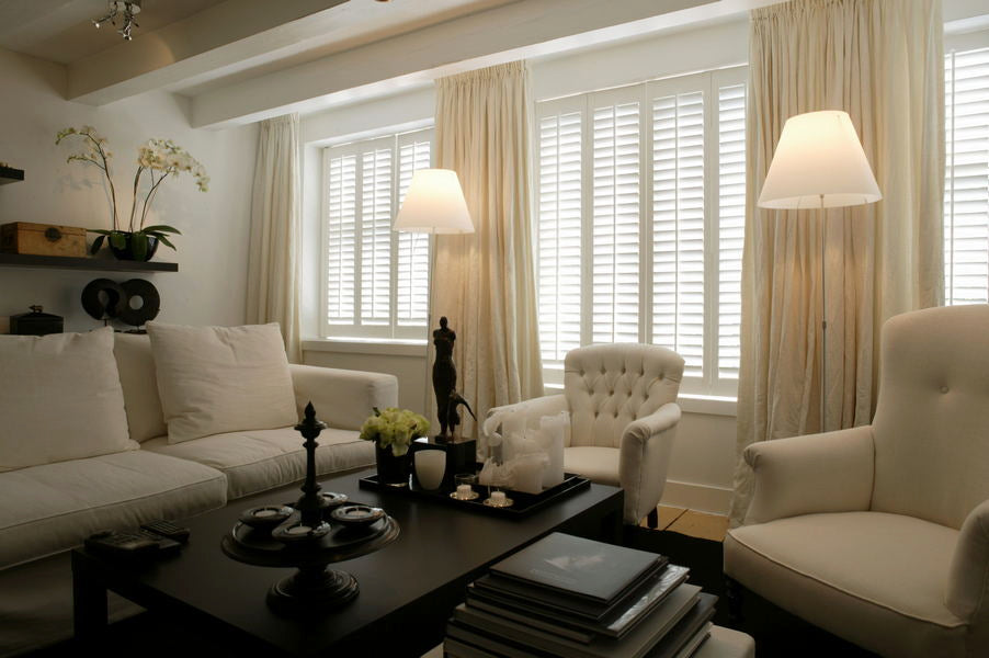 elegant living room in pastel colour with white sofas, white shutters and cream curtains