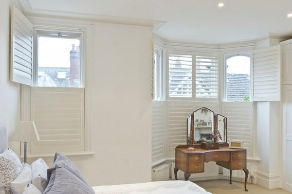bedroom with two windows with tier on tier shutters, top half open