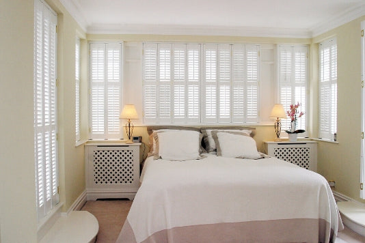 white bedroom with large window and white shutters