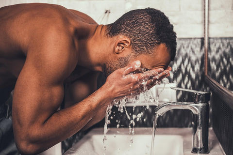 man washing face at sink to clean body hair
