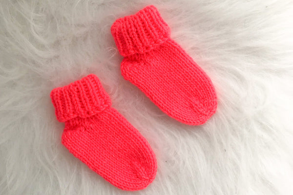 Pair of newborn socks in neon coral on white background