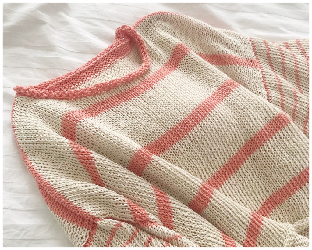 Cream and Peach handknitted cotton stripe tee shirt lying on white bed