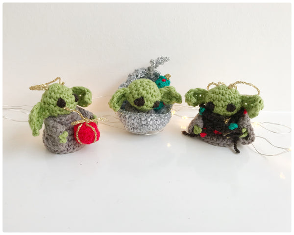 3 baby yoda Christmas tree decorations with fairy lights behind