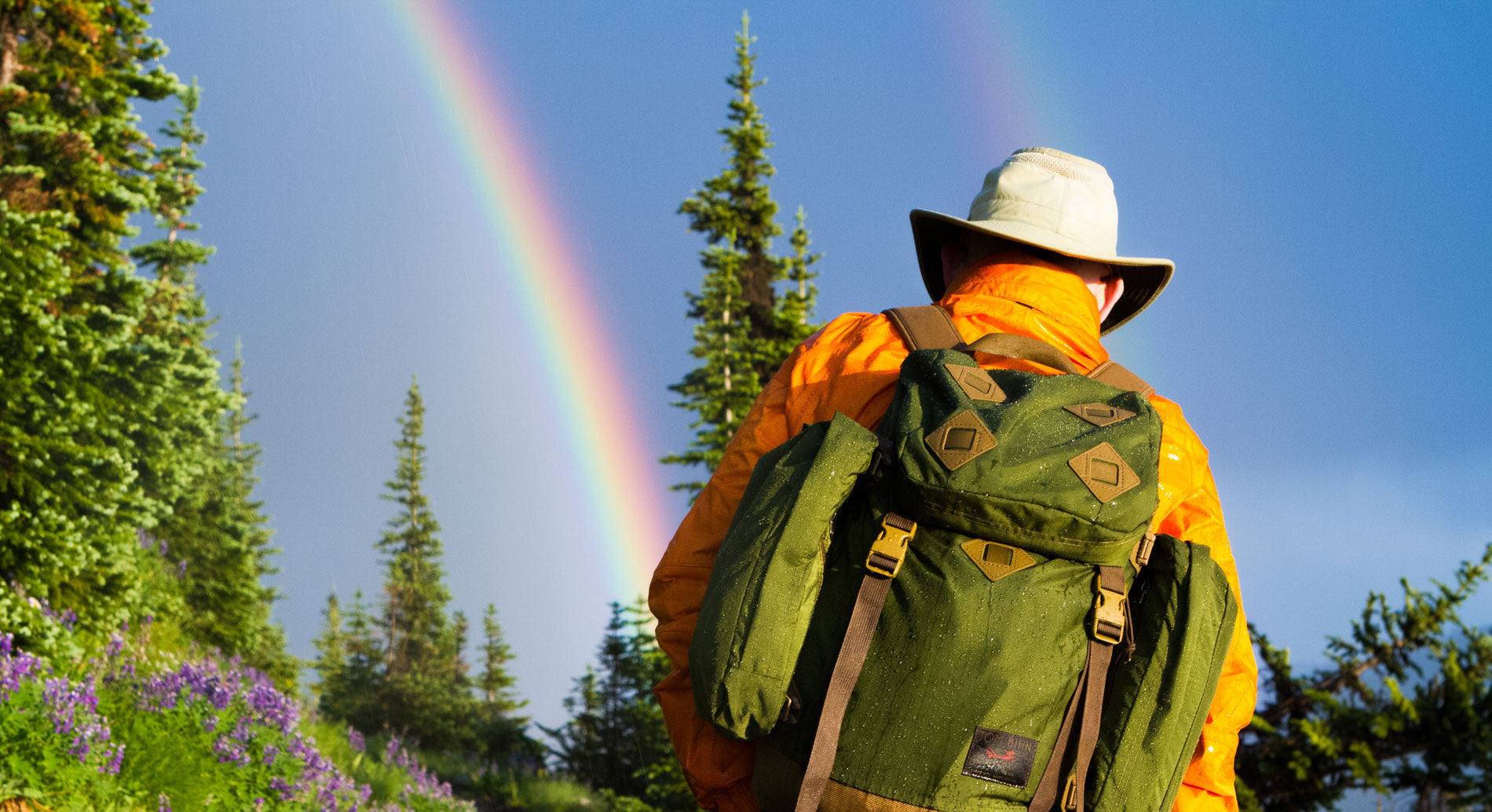 Tom hiking wearing a Guide's Pack and there is a rainbow!