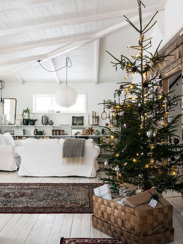 Rustic white living room interior with shelves, white sofa and a sparse Christmas tree