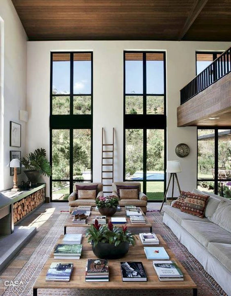 Large restful two story room with floor to ceiling windows allowing indirect sunlight into the room.