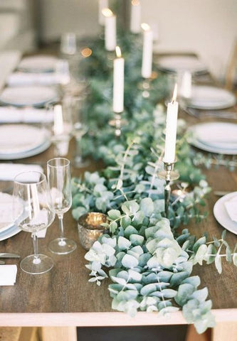 Table setting with white candles and white plates on a wooden table