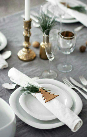 Christmas table setting on grey table cloth with wooden Christmas tree on napkin