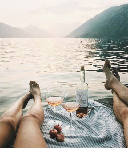 Man and woman relaxing at a lake, enjoying wine