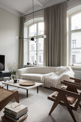 Minimalist interior with white sofa, brown chairs and cream curtains