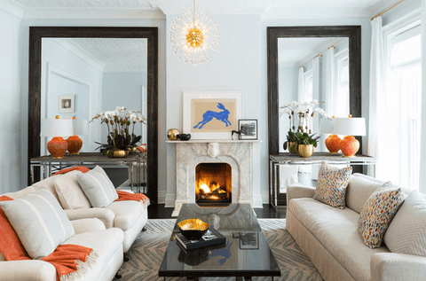 Living room with two big mirrors, orange throw and lamps