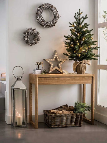 Hall table decorated for the holidays with star shaped light, small Christmas tree and two twig wreaths on the wall