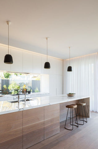 kitchen with white marble island, two bar stools and 3 hanging lights over island