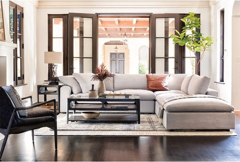 Stylish living room interior with dark timber flooring, fire place, cream sofa and brown wooden framed windows and doors