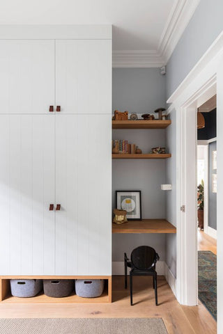 Room with white cupboard, brown shelves and table at the side