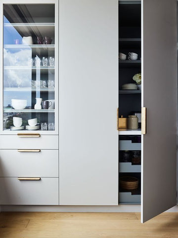 Tall grey cabinet with drawers filled with kitchenware