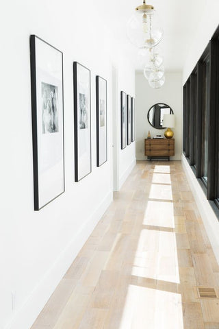 Brightly lit hallway with black framed pictures on white wall