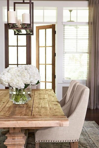 Dining table with fresh cut hydrangea flowers in a glass vase on top.