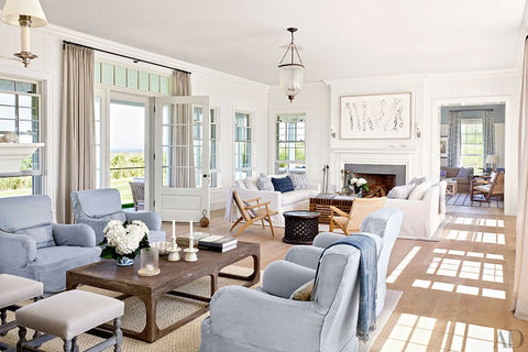 Hamptons style living room with pale blue and white slip covered sofas. White walls, timber floors, pendant lighting and fireplace.