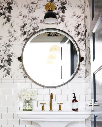 Small powder room with floral wallpaper, subway tile and a round mirror