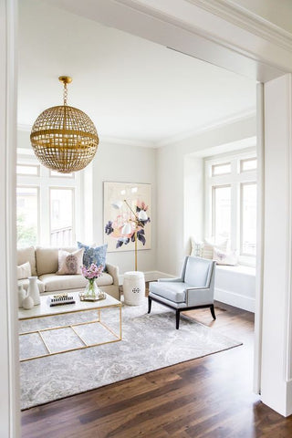 White living room interior decor with cream sofa, light blue chair and globe pendant light
