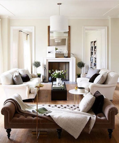White living room interior with a fire place, white sofas and a brown day bed.